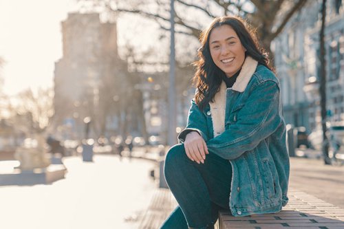 Girl sitting on a wall in a city park on a sunny day smiling at the camera.jpg