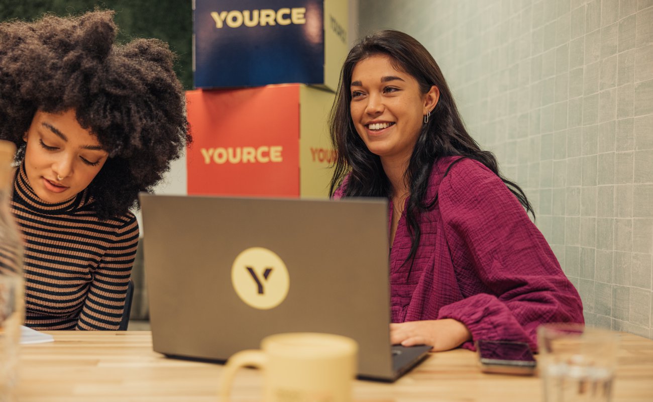 Two girls with laptop smiling during meeting
