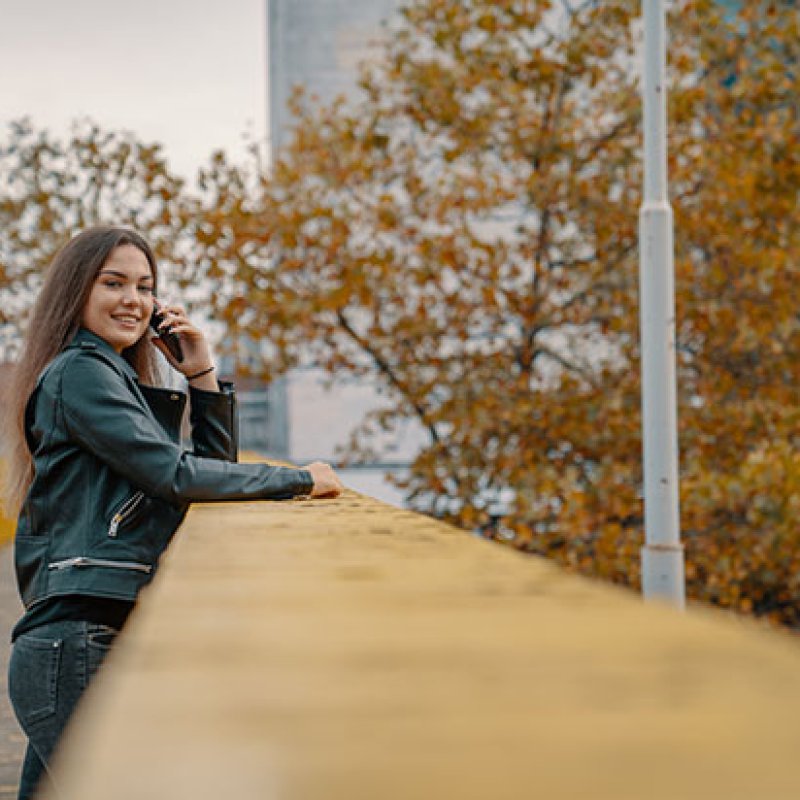 Girl leaning on bannister while calling looking into camera smiling (Horizontal) 2.jpg