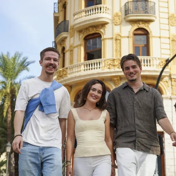 Drie collega's lopen lachend door een Spaanse stad