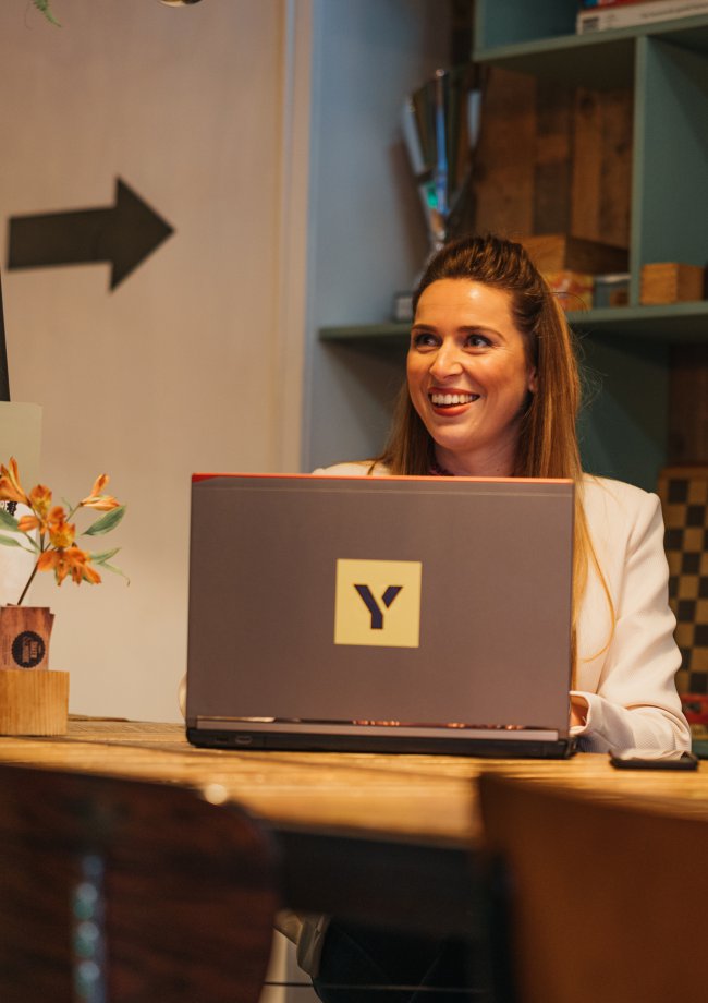 Girl behind laptop smiling looking to colleague